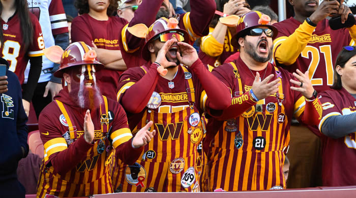 Commanders fans in overalls cheer from the stands.